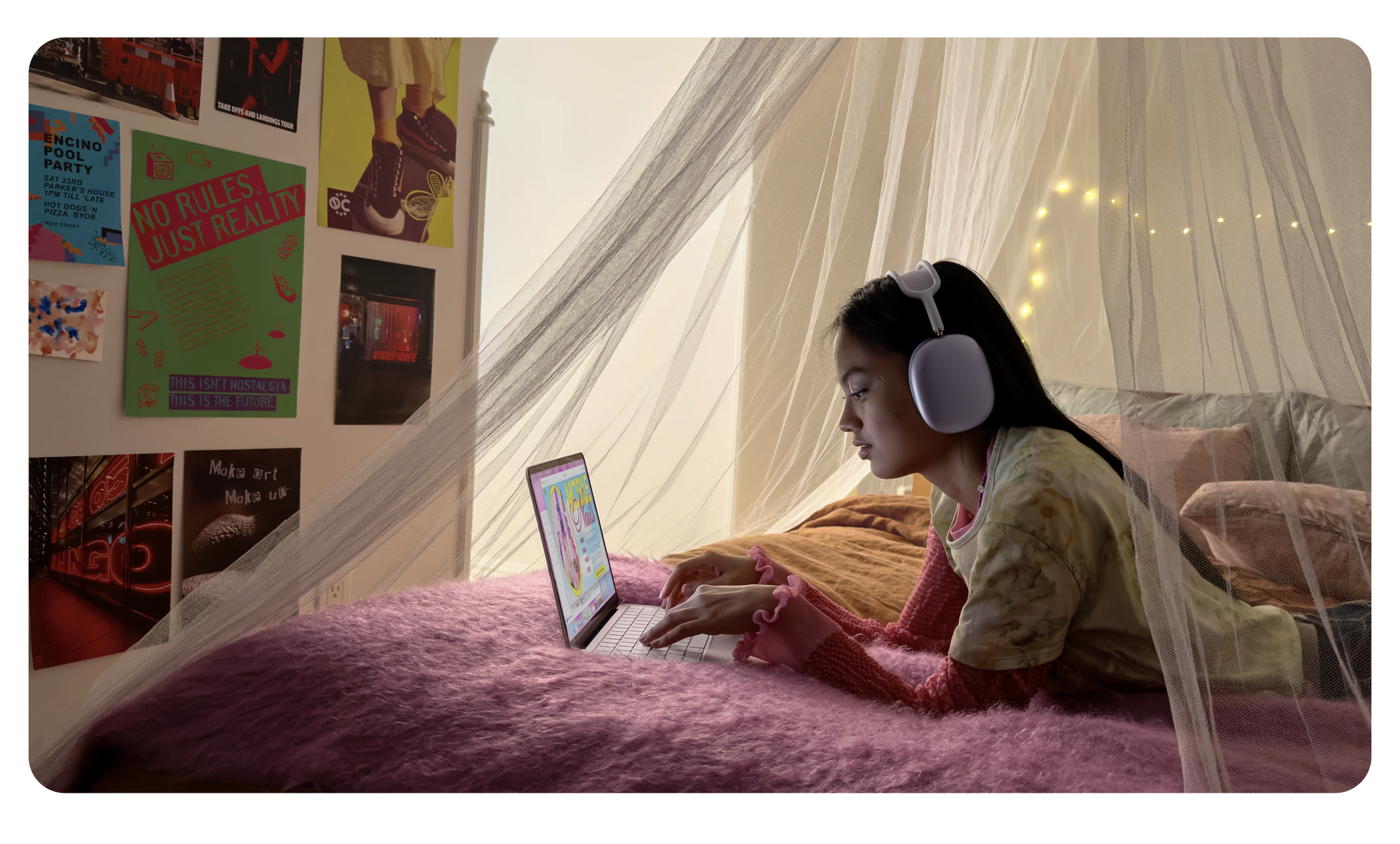 A child using a MacBook Neo while wearing AirPods Max on a bed.