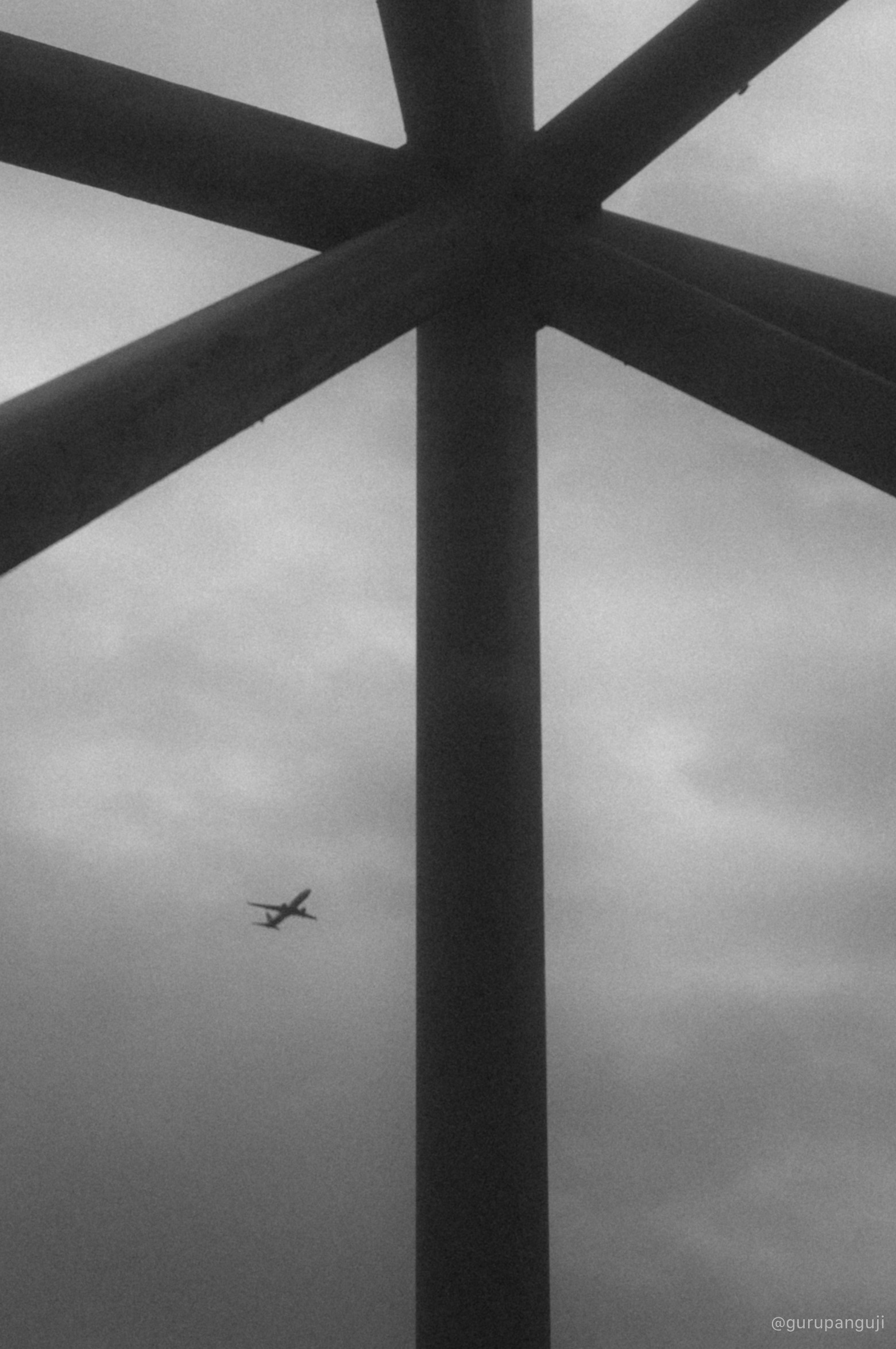 Airplane passing beneath geometric steel beams