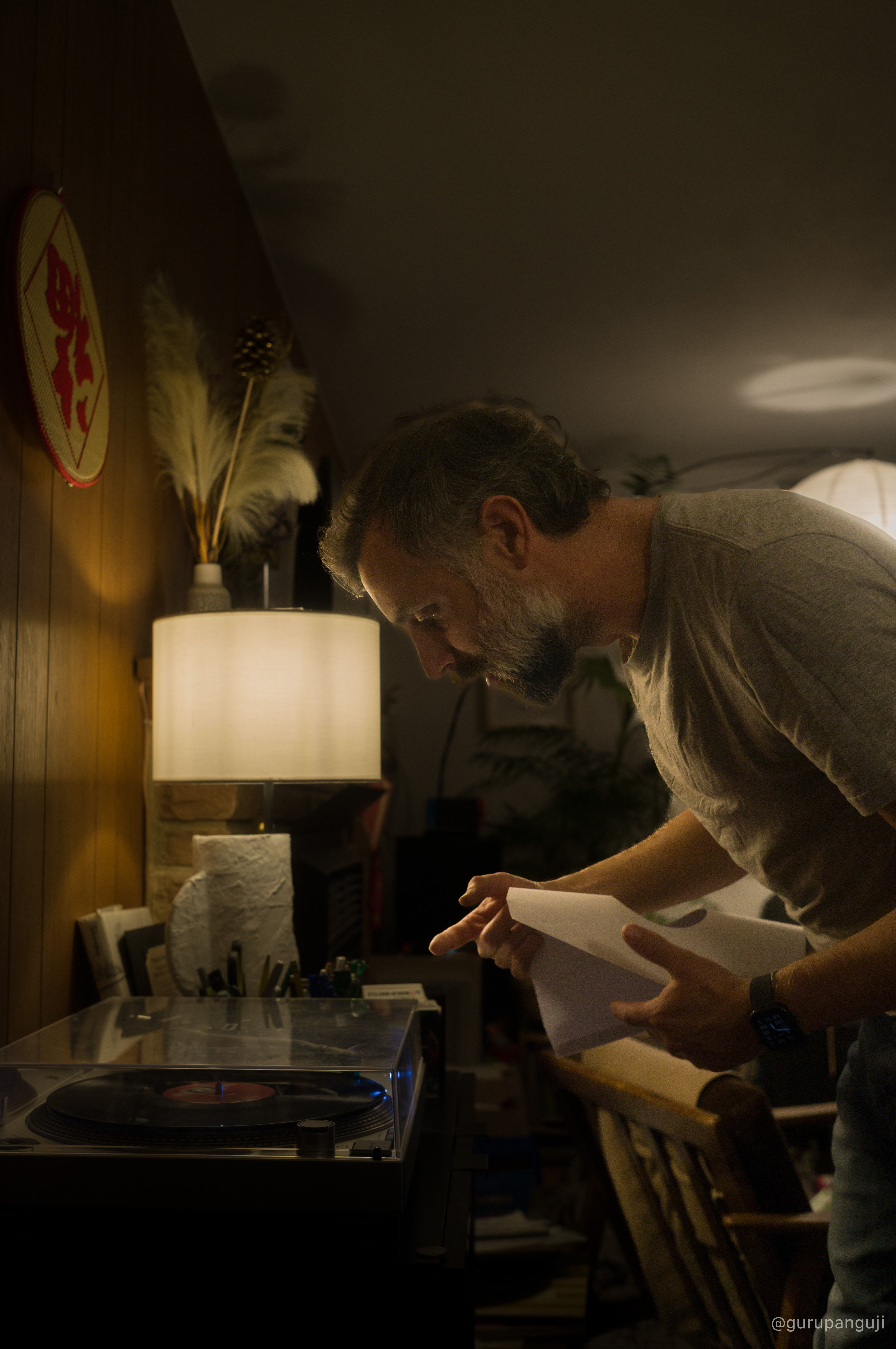 Man cueing a record on a turntable in warm indoor light